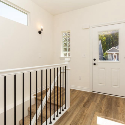 Bright and open entryway with white walls and hardwood flooring